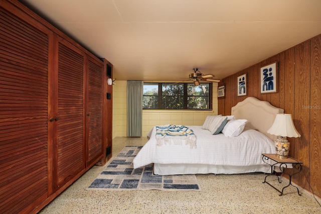 bedroom with speckled floor and wood walls