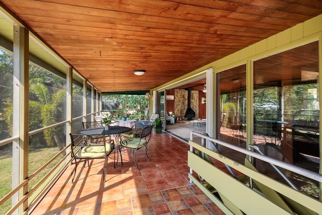 sunroom with plenty of natural light, wooden ceiling, and a wood stove