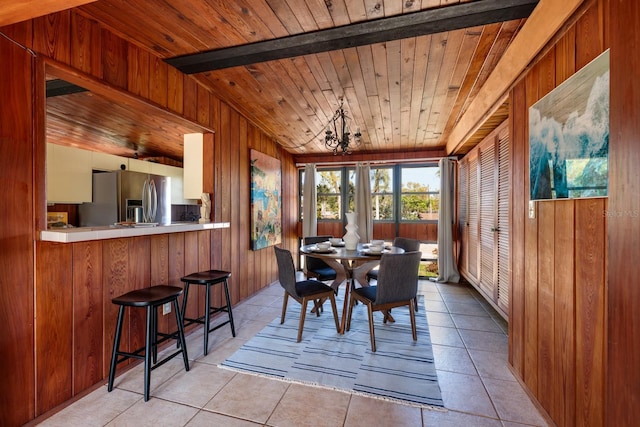 dining space with light tile patterned floors, wooden walls, and wooden ceiling