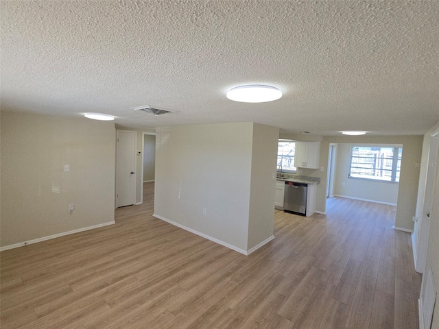 spare room with light wood finished floors, baseboards, and visible vents