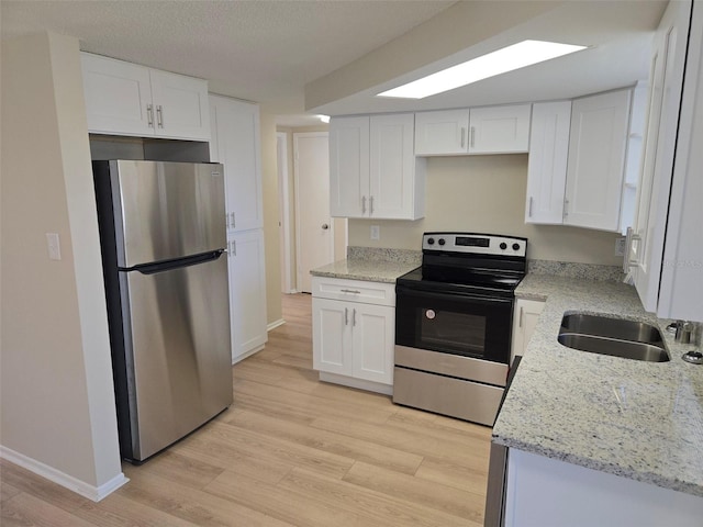 kitchen with white cabinets, light wood-style flooring, and stainless steel appliances