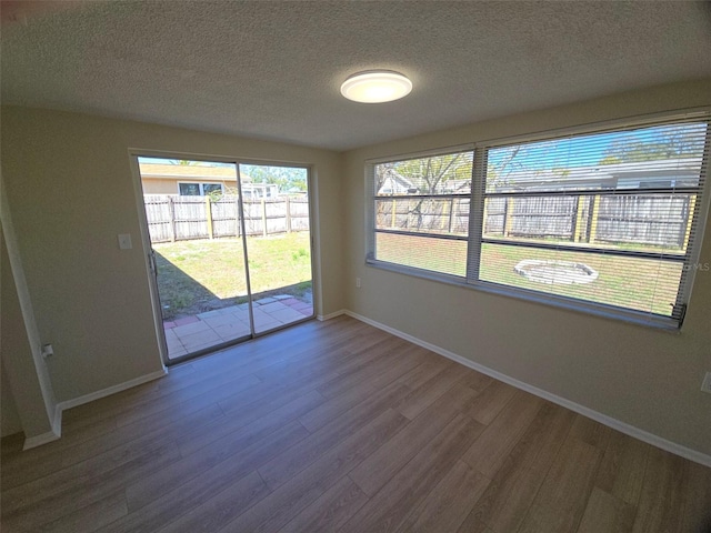 spare room featuring a textured ceiling, baseboards, and wood finished floors