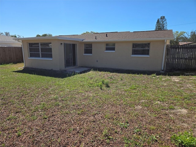 back of house featuring a yard, fence, and stucco siding