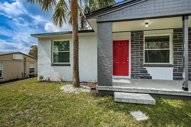 view of exterior entry featuring central air condition unit, a lawn, and stucco siding