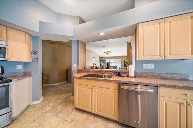 kitchen featuring lofted ceiling, dark countertops, appliances with stainless steel finishes, light brown cabinets, and a sink