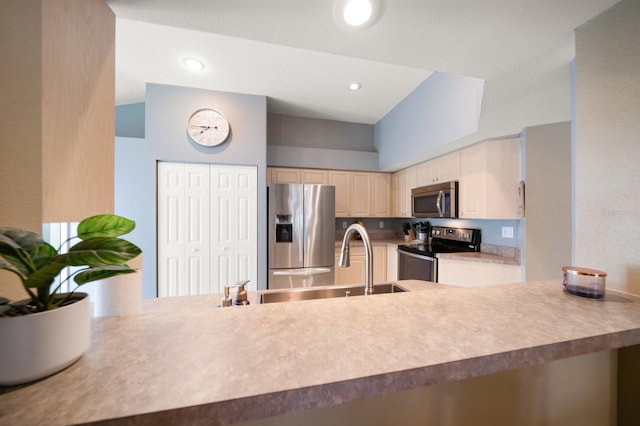 kitchen featuring stainless steel appliances, cream cabinetry, a peninsula, and recessed lighting