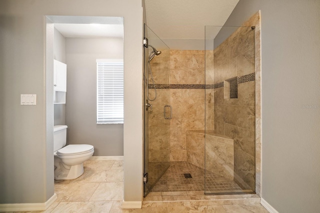 bathroom featuring toilet, a stall shower, and baseboards