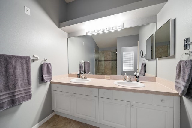 bathroom featuring a stall shower, a sink, baseboards, and double vanity