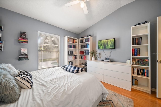 bedroom featuring vaulted ceiling, ceiling fan, a textured ceiling, and light wood-type flooring