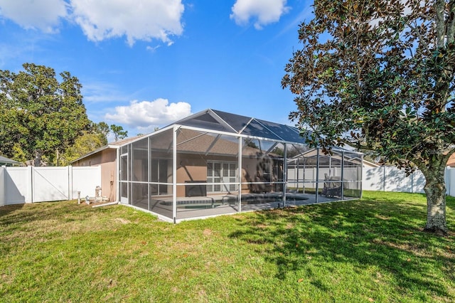 rear view of house featuring a yard, a patio area, a fenced backyard, and glass enclosure