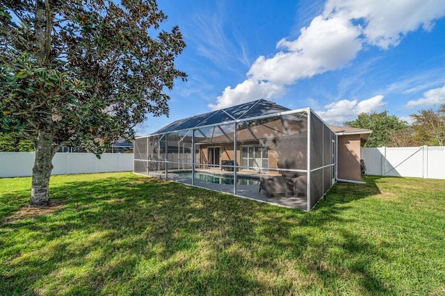 rear view of house featuring a yard, a fenced backyard, a fenced in pool, and a lanai