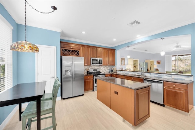 kitchen with visible vents, a kitchen island, appliances with stainless steel finishes, a peninsula, and a sink