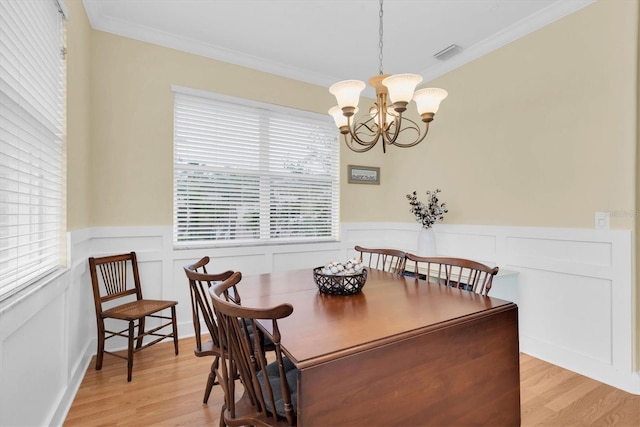 dining space featuring light wood finished floors, visible vents, an inviting chandelier, and ornamental molding