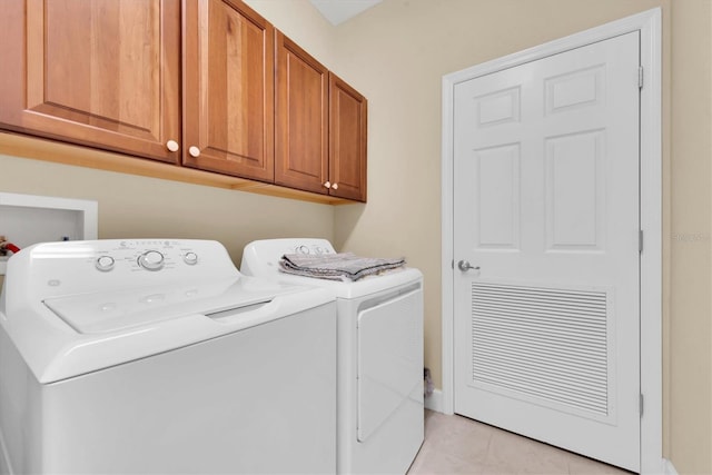 laundry area with washing machine and dryer, cabinet space, and light tile patterned floors