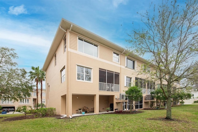 rear view of property featuring a lawn and stucco siding