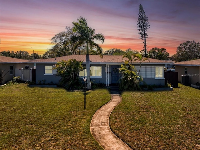 single story home featuring cooling unit, a lawn, and fence