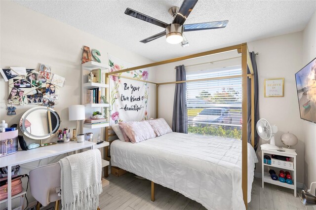 bedroom with a textured ceiling, wood finished floors, and a ceiling fan