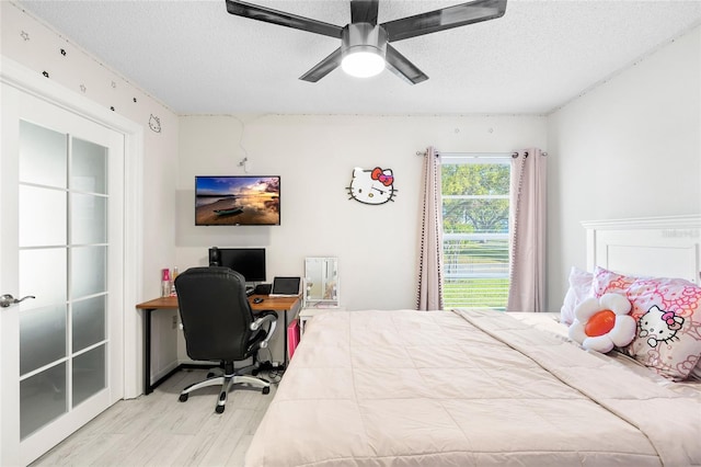 bedroom with ceiling fan, a textured ceiling, and wood finished floors