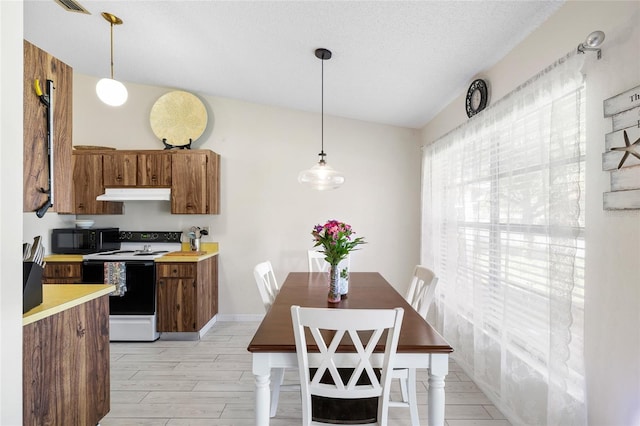 kitchen with black microwave, under cabinet range hood, light countertops, brown cabinetry, and white electric range