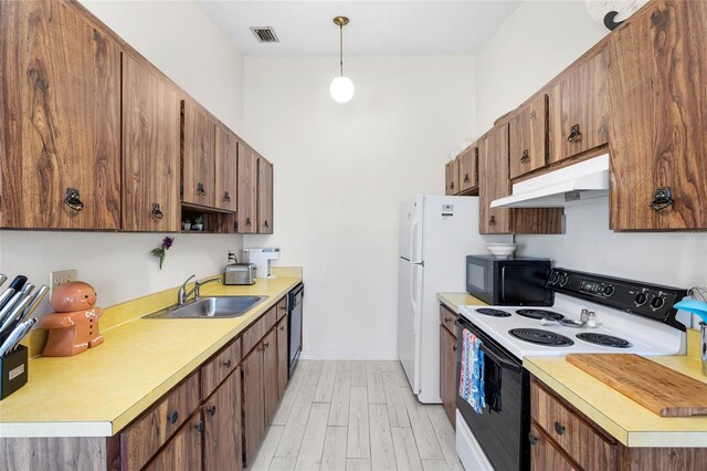 kitchen featuring visible vents, a sink, black appliances, light countertops, and under cabinet range hood