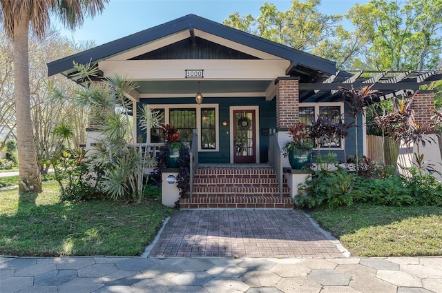 entrance to property with covered porch and a lawn