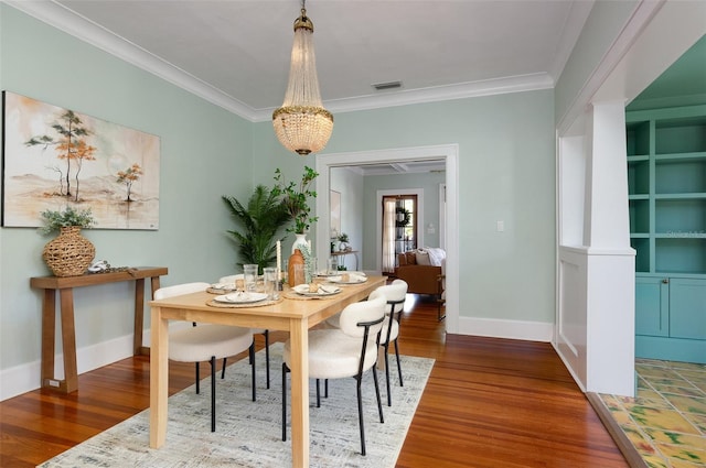 dining space with visible vents, baseboards, wood finished floors, and crown molding