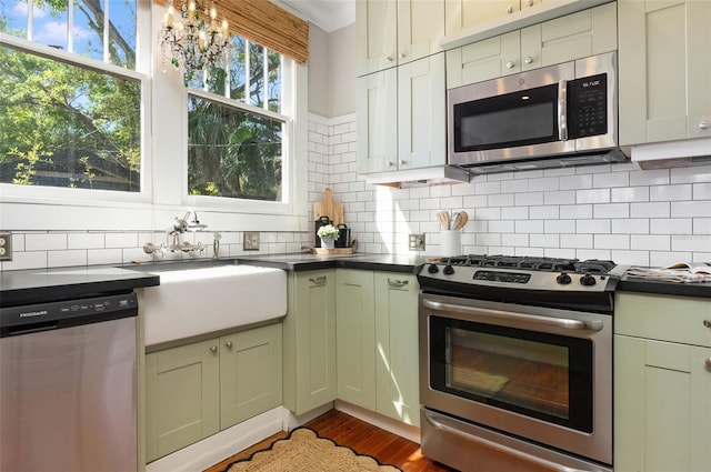 kitchen featuring a sink, stainless steel appliances, dark countertops, and dark wood-style floors