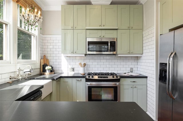 kitchen with green cabinetry, stainless steel appliances, backsplash, and a sink