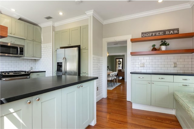 kitchen featuring dark countertops, visible vents, crown molding, appliances with stainless steel finishes, and wood finished floors