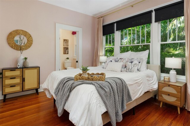 bedroom with wood finished floors and connected bathroom