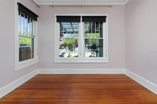 spare room with baseboards, wood finished floors, and crown molding