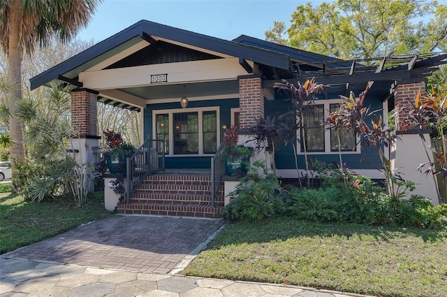 view of front of property with brick siding, a porch, and a front lawn