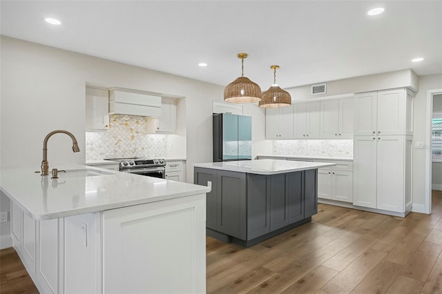 kitchen with premium range hood, visible vents, a sink, light countertops, and appliances with stainless steel finishes