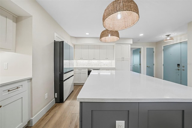 kitchen featuring tasteful backsplash, a kitchen island, light countertops, freestanding refrigerator, and light wood-style floors