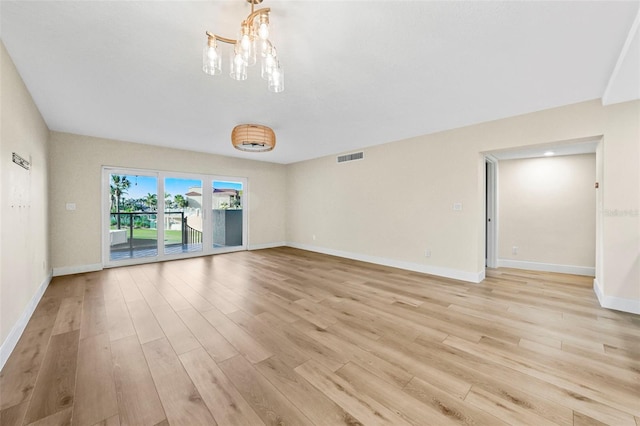 unfurnished room featuring visible vents, baseboards, light wood-style floors, and a notable chandelier