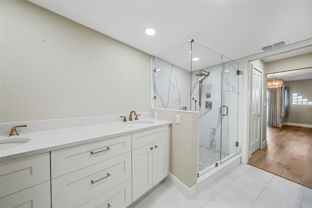 bathroom with double vanity, visible vents, a marble finish shower, and a sink