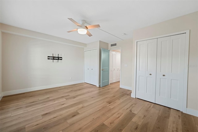 unfurnished bedroom featuring visible vents, two closets, baseboards, light wood-type flooring, and a ceiling fan