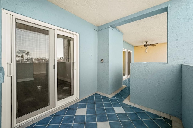 bathroom featuring a ceiling fan, a textured wall, and a textured ceiling