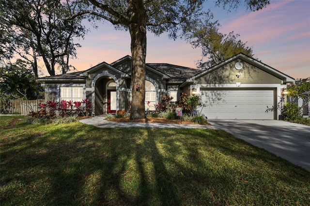 single story home featuring a garage, a lawn, concrete driveway, fence, and stucco siding