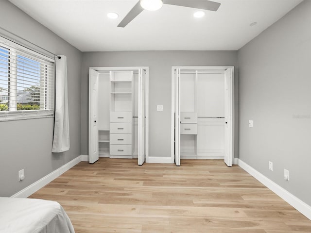 unfurnished bedroom with baseboards, light wood-style floors, and multiple closets