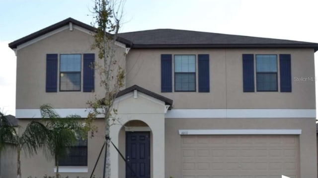 view of front of property featuring stucco siding, a garage, and driveway