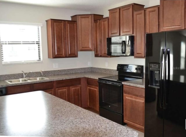 kitchen with a sink, black appliances, brown cabinetry, and light countertops