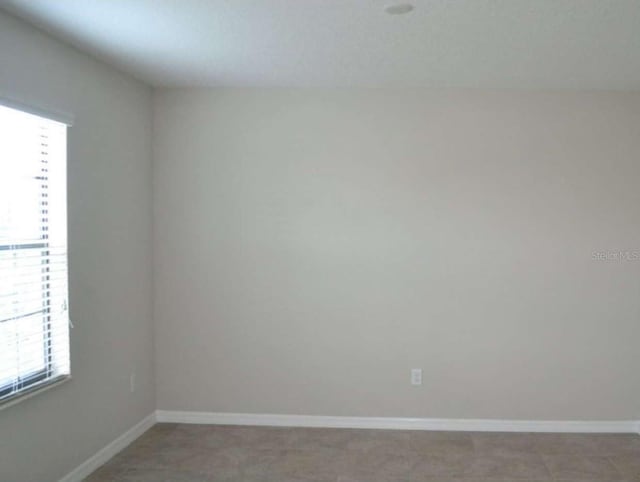 unfurnished room with baseboards