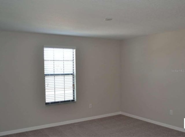 carpeted spare room with baseboards