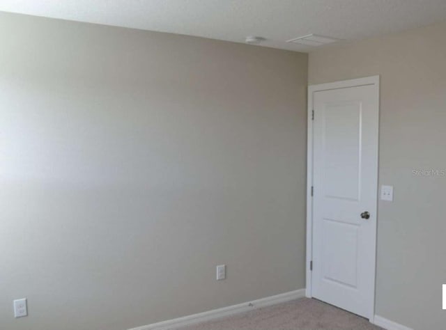 spare room featuring baseboards and light carpet