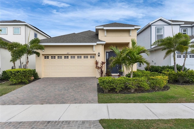 view of front facade featuring roof with shingles, decorative driveway, an attached garage, and stucco siding