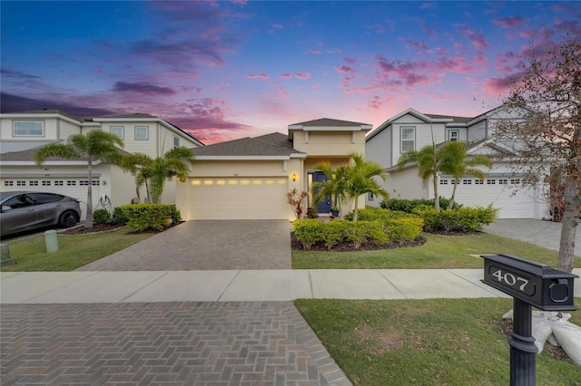 view of front facade featuring a garage, decorative driveway, a lawn, and stucco siding