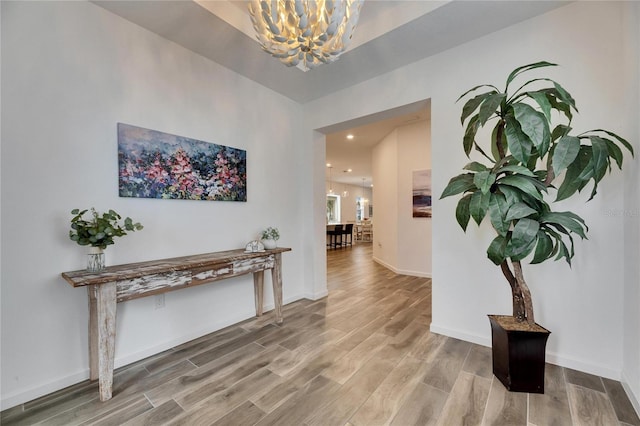 hall with a notable chandelier, baseboards, and wood finished floors