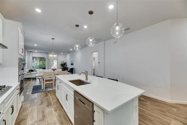 kitchen featuring stainless steel appliances, light wood-style floors, open floor plan, and a sink