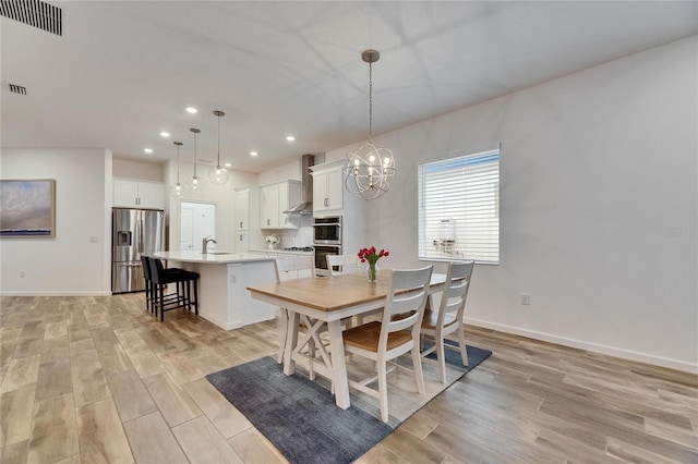 dining room featuring a notable chandelier, light wood finished floors, recessed lighting, visible vents, and baseboards